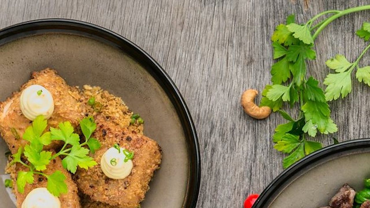 Golden breaded patties with fresh herbs on a dark plate